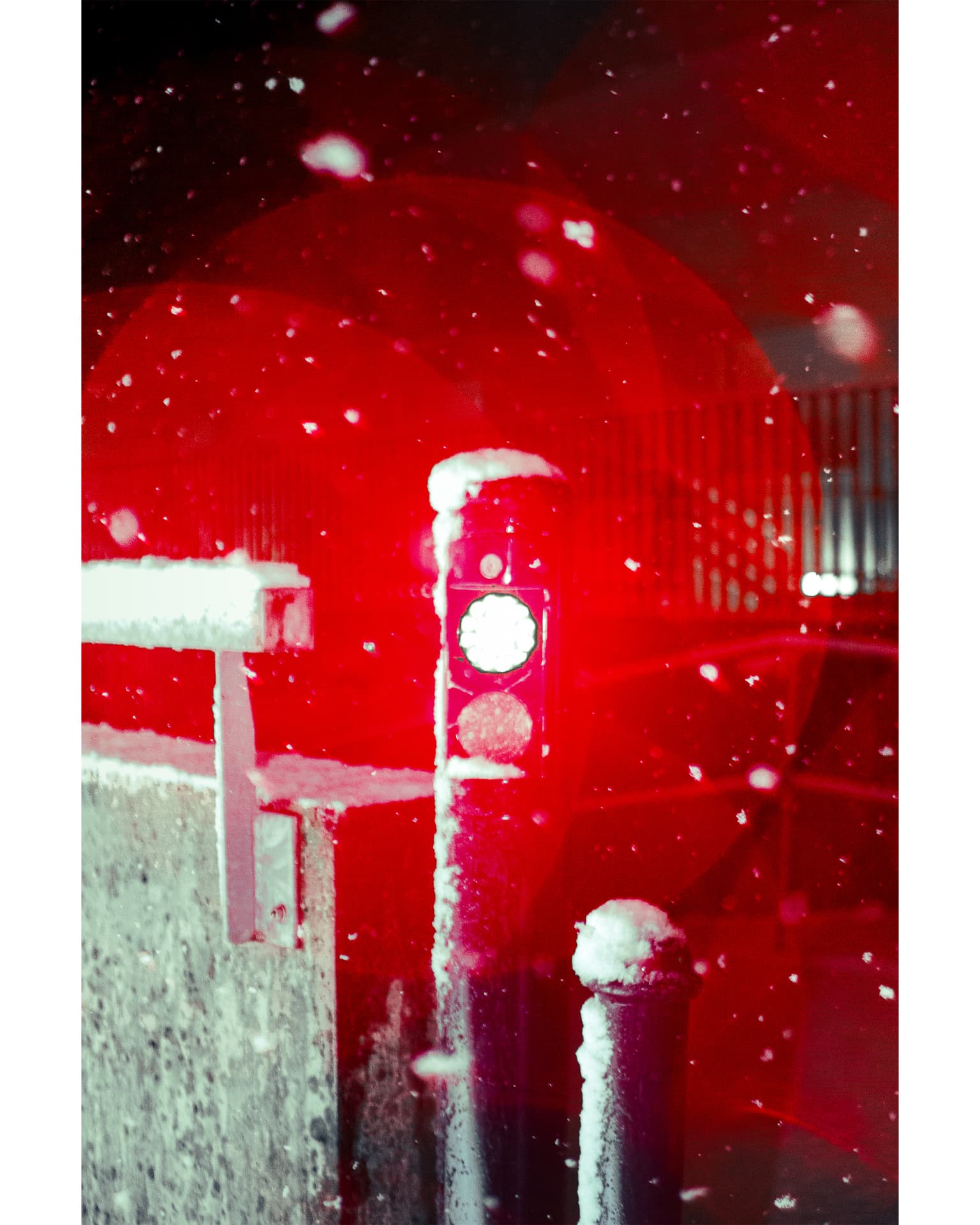 A snow-covered pedestrian signal glowing red